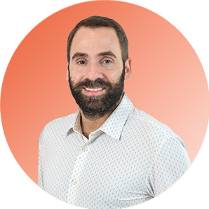 Un homme barbu aux cheveux courts, vêtu d'une chemise boutonnée de couleur claire, sourit sur un fond orange dégradé au marché public de l'AMO.